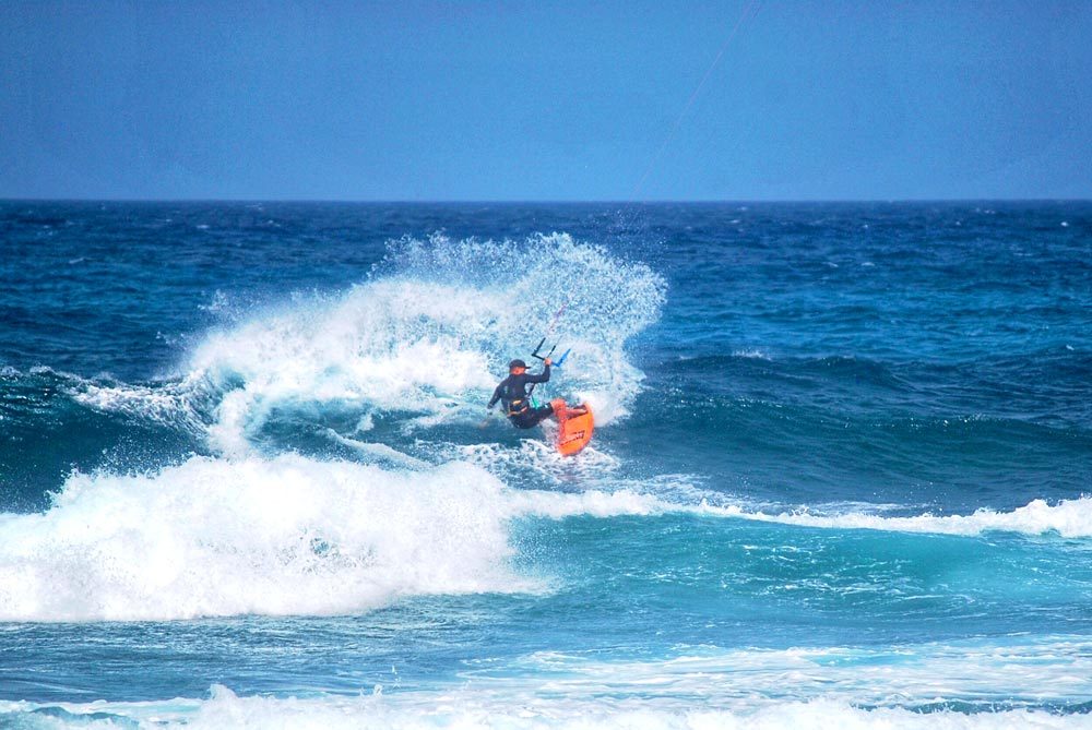 Kitesurfista saltando una ola