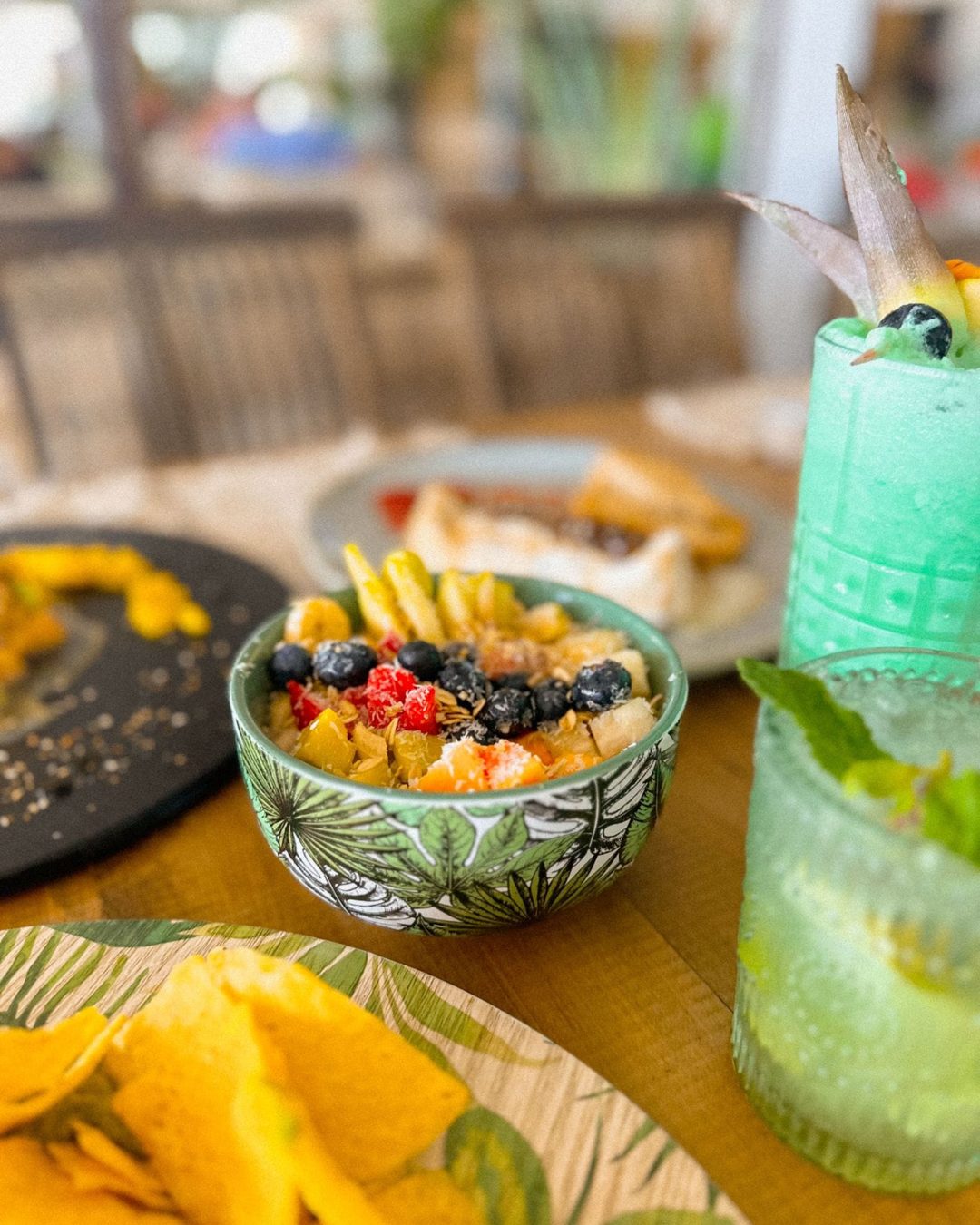 Bowl de fruta, nachos y cócteles en una mesa de la terraza de Banana Beach Club